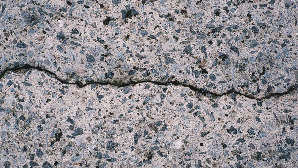 How Stamped Concrete Patios Perform in Freeze-Thaw Climates cracked exposed-aggregate concrete close-up