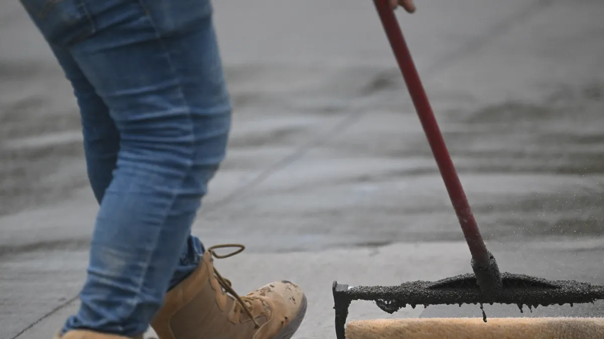 How to Protect a Stamped Concrete Patio from UV Fading Person rolling coating on a concrete surface