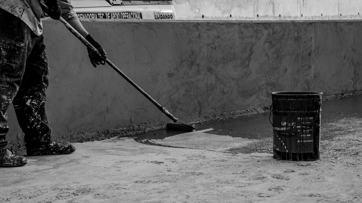 Worker applying coating to a concrete floor