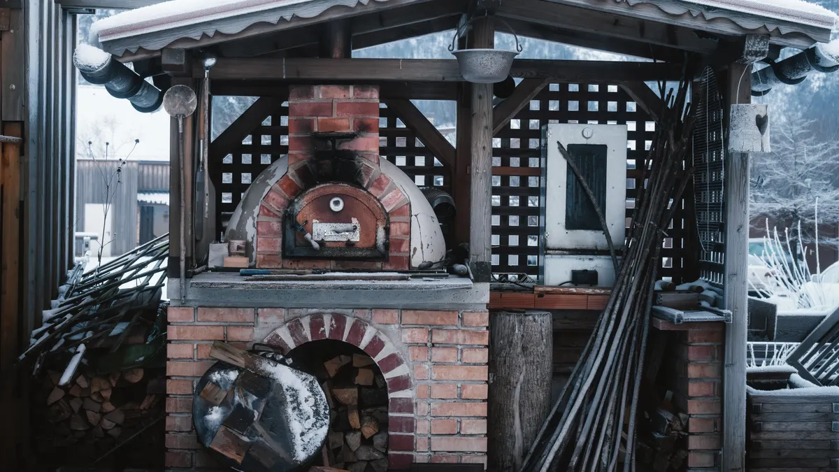 Brick outdoor pizza oven under a patio roof