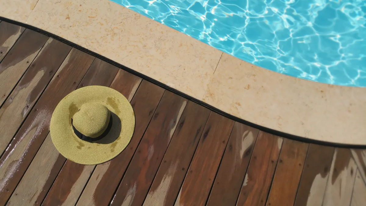 Stamped Concrete Patio Designs for Pool Areas Pool edge beside a wooden deck and hat